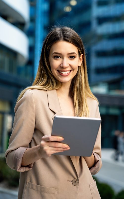 successful-businesswoman-using-a-digital-tablet-while-standing-in-front-of-business-building.jpg